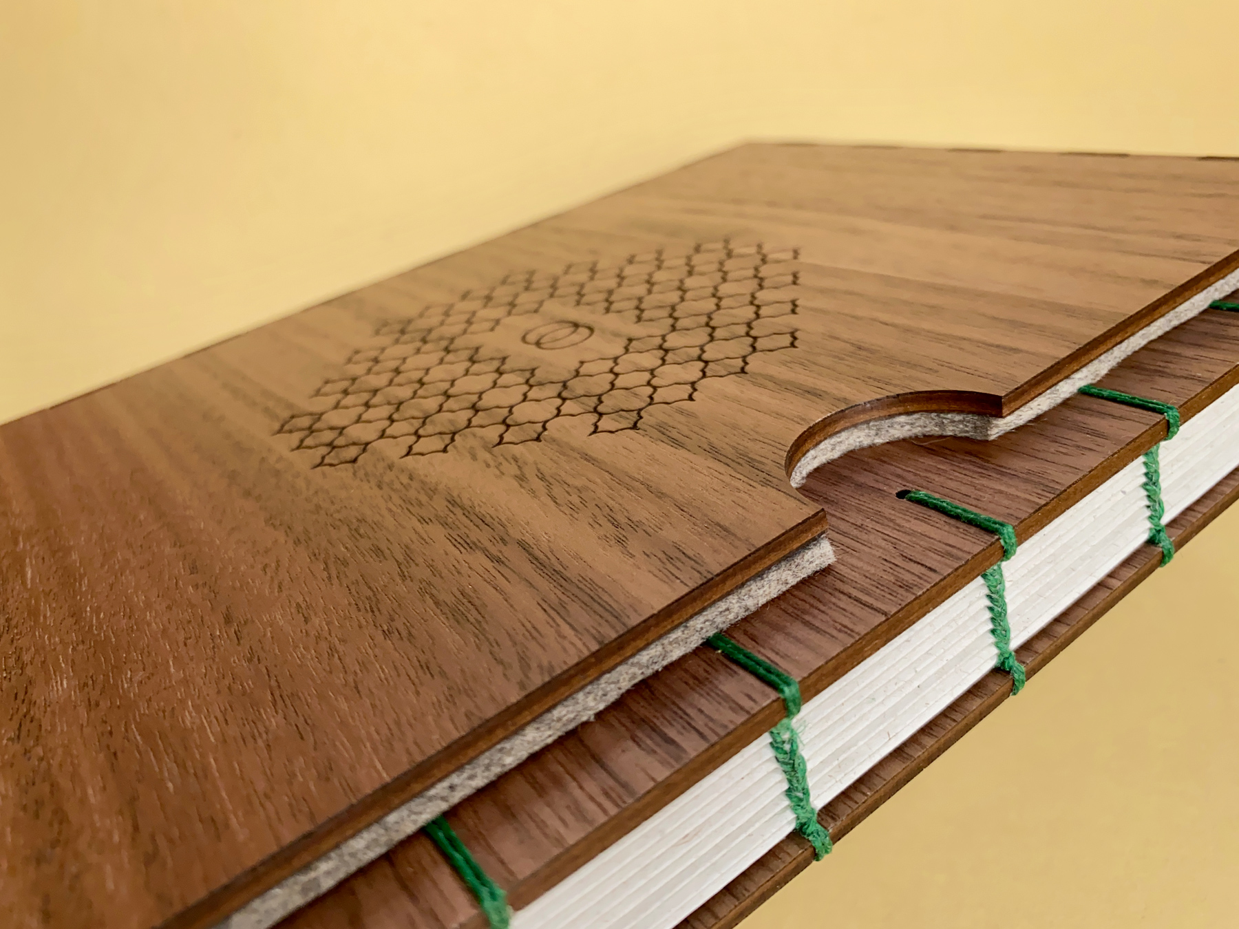 A 40th birthday Fondfolio we made last month. The book has a walnut cover and a custom walnut slipcase. It’s bound with moss green linen thread and is laying across a pale yellow background.