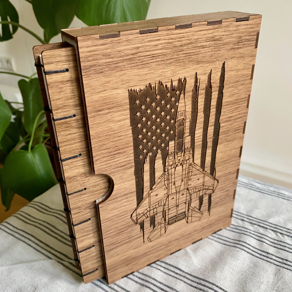 A retirement Fondfolio and slipcase for a US Air Force pilot. Walnut wooden covers, coptic bound, the book is pictured in its slip case engraved with a Fighter Jet with an American flag behind it.