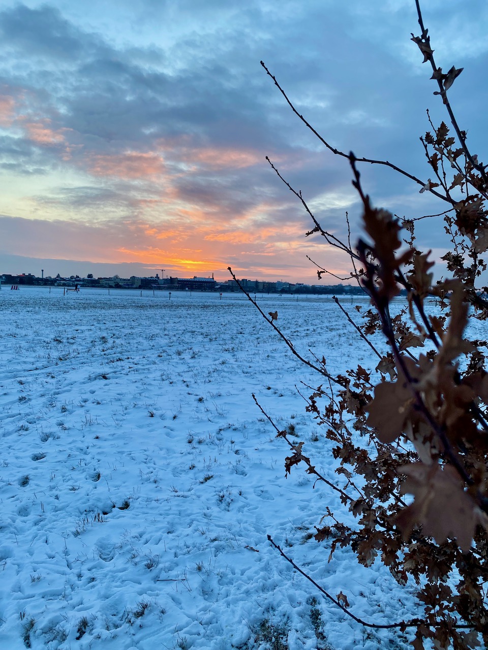 The best of the sunset sliver, snow covered field with a patch of bright orange and yellow.